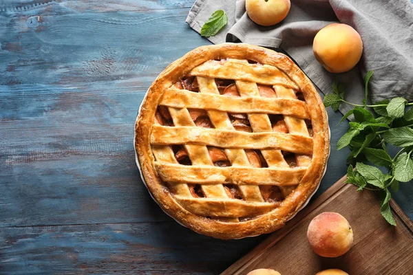 Plate with delicious peach pie on wooden table
