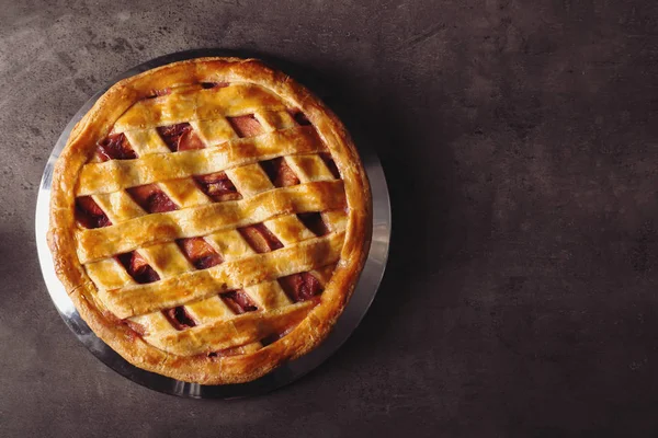 Plate with delicious peach pie on dark table