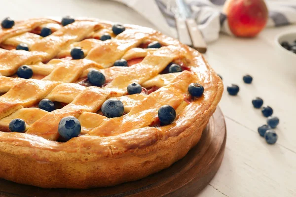 Delicious peach pie with blueberry on wooden table, closeup