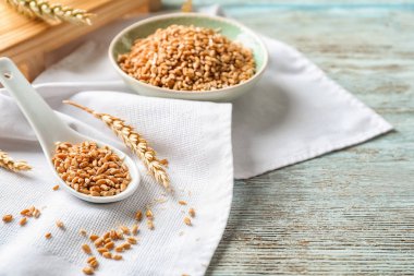 Kase ve ahşap masa üzerinde Ham buğday kaşıkla