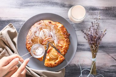 Ahşap masanın üstüne pudra şekeri ile şeftali Galette'ye yağmurlama kadın