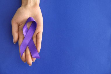 Woman holding purple ribbon on color background. Pancreatic cancer awareness concept clipart