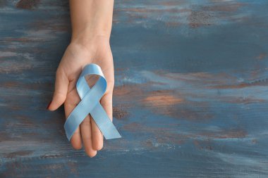 Mavi kurdele ahşap arka plan üzerinde tutan kadın. Prostat kanseri kavramı