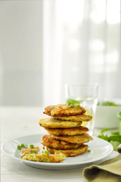 Plate with stack of zucchini pancakes on table