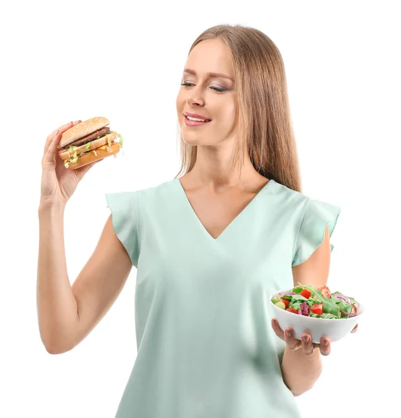 新鮮な野菜のサラダと白い背景のハンバーガーとの間を選択する美人 — ストック写真