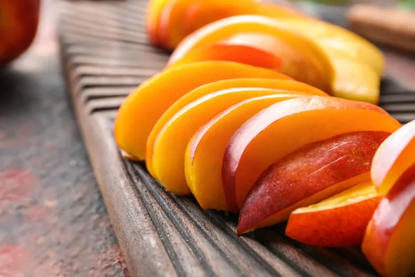 Fresh sliced peaches on wooden board, closeup