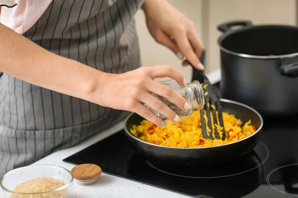 Woman cooking rice on stove in kitchen, closeup