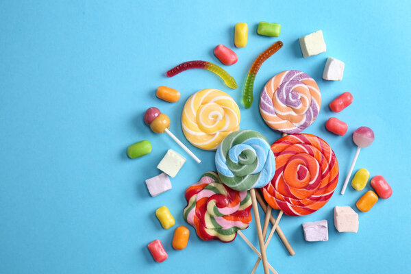 Delicious lollipops and candies on color background