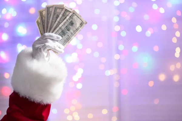 Рука Санта Клауса Держит Долларовые Купюры Против Разряженных Огней — стоковое фото