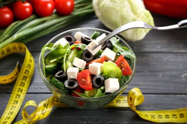 Peynir ve kase ahşap masa üzerinde sağlıklı taze salata çatalı. Diyet kavramı