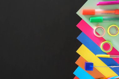 Renkli karton yaprak ve koyu arka plan üzerinde okul kırtasiye