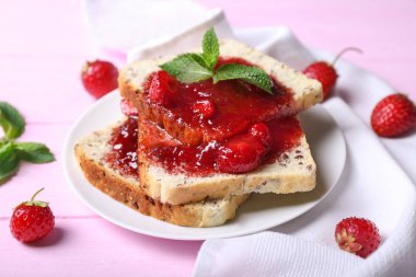 Dilim ekmek ve renk ahşap masa üzerinde lezzetli çilek reçeli ile plaka