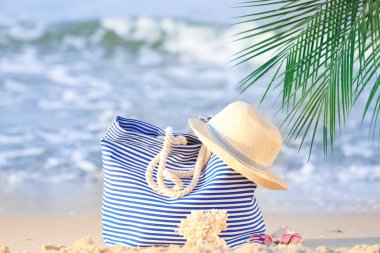 Şapka ve güneş gözlüğü kum deniz kenarında üzerinde plaj çantası