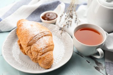 Lezzetli kruvasan ve hafif tabloda çay ile plaka