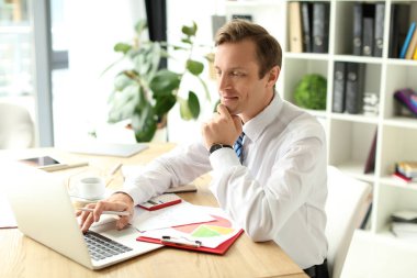 İşadamı ofiste dizüstü bilgisayarla çalışıyor.