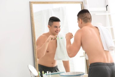 Genç adam banyoda dişlerini fırçalıyor.