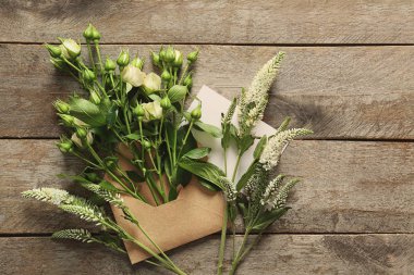 Ahşap arka plan üzerinde çiçekler olan açık posta zarf