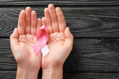 Pembe kurdele ahşap arka plan üzerinde tutan kadın. Meme kanseri kavramı