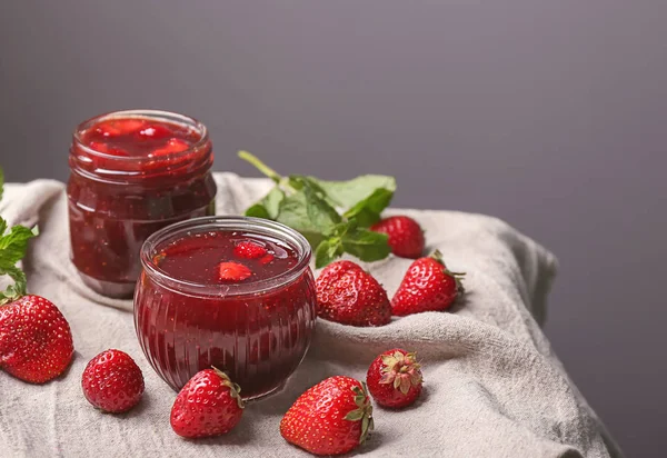 Glazen Potten Met Heerlijke Aardbei Jam Tabel Tegen Grijze Achtergrond — Stockfoto