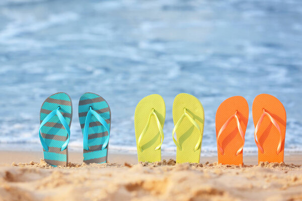 Set of beach flip-flops on sand near sea