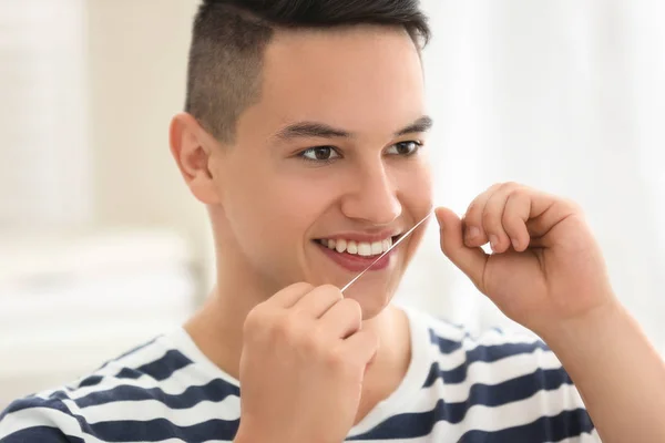 Young man flossing teeth at home