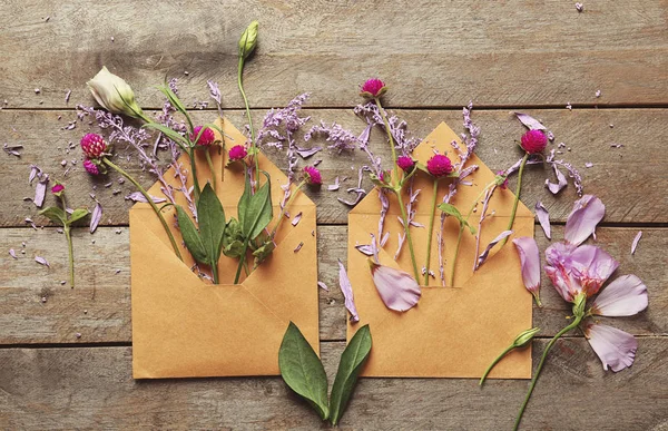 Open mail envelopes with flowers on wooden background