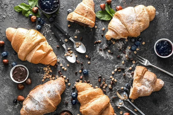 Tasty croissants with chocolate paste and jam on grey background
