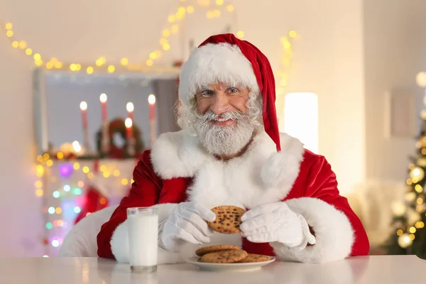 Santa Claus Jeść Ciasteczka Mleko Spożywcze Przy Stole Pokoju Urządzonego — Zdjęcie stockowe