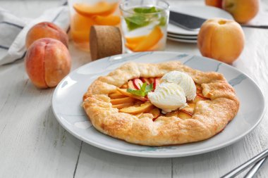 Plaka lezzetli şeftali Galette'ye ve beyaz ahşap masa üzerinde dondurma ile