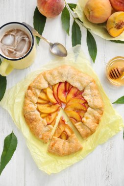 Parşömen lezzetli şeftali Galette'ye ve serinletici içecek beyaz tahta masada Kupası