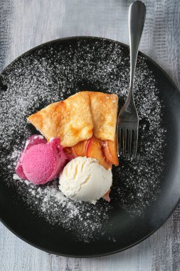 Lezzetli şeftali Galette'ye ve dondurma ahşap masa üzerinde parça ile plaka