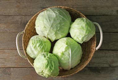 Ahşap masa üzerinde taze lahana ile hasır sepet