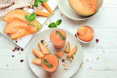 Beyaz ahşap masa üzerinde lezzetli kavun güler yüzlü ile kompozisyon