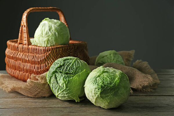 Fresh cabbage with basket on wooden table