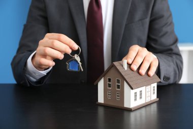 Emlakçı ile ev modeli ve anahtar karanlık masada. İpotek kavramı