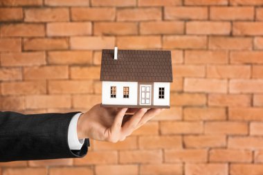 Emlakçı ile ev modeli duvara karşı el. İpotek kavramı