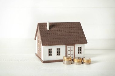 Ev modeli ve sikkeler üzerinde beyaz tablo. İpotek kavramı