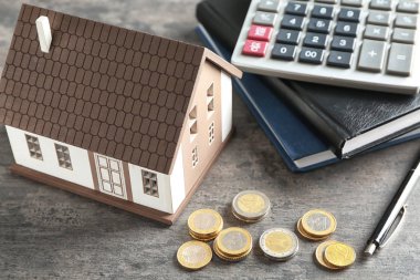 Ev modeli, hesap makinesi ve sikkeler üzerinde gri tablo. İpotek kavramı
