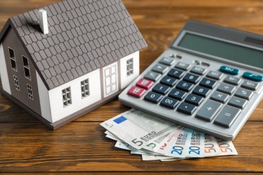 Ev modeli, hesap makinesi ve Lirası ahşap masa üstünde. İpotek kavramı