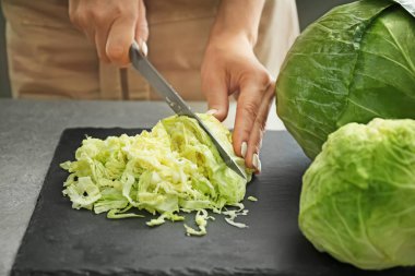 Woman cutting fresh cabbage, closeup clipart