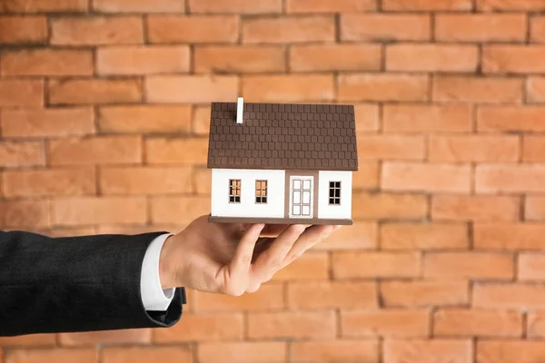 Hand Eines Immobilienmaklers Mit Hausmodell Gegen Ziegelwand Hypothekenkonzept — Stockfoto