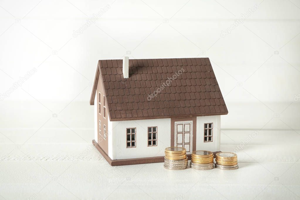 House model and coins on white table. Mortgage concept