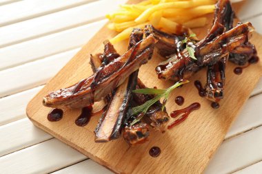 Patates kızartması ve ahşap tahta üzerinde sos ile lezzetli ızgara kaburga