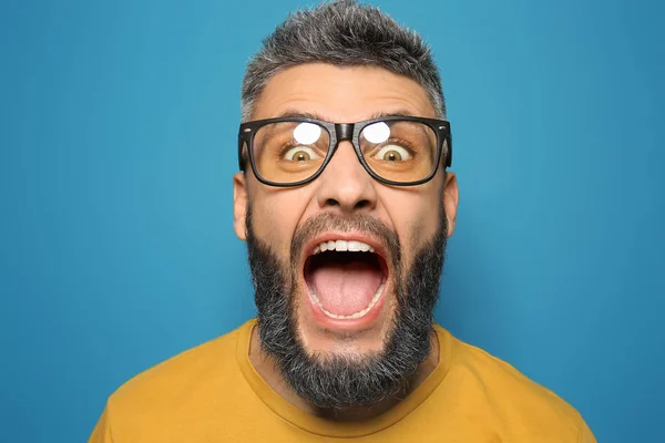 Portrait of screaming man with dyed hair and beard on color background