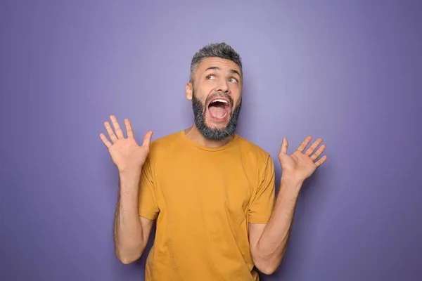 Portrait of emotional man with dyed hair and beard on color background