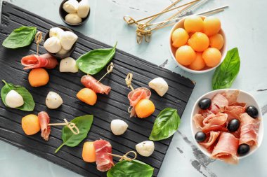 Lezzetli kavun topları ahşap tahta üzerinde jambon ve mozzarella peyniri ile