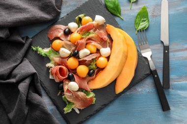 Lezzetli kavun topları kayrak plaka üzerinde jambon ve mozzarella peyniri ile