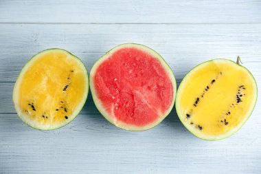 Beyaz ahşap masa üzerinde sarı ve kırmızı karpuz yarısı