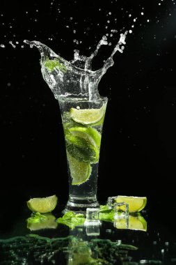 Koyu arka plan üzerinde sıçraması ile taze Mojito cam