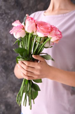 Güzel gül buketi gri arka plan üzerinde tutan kadın